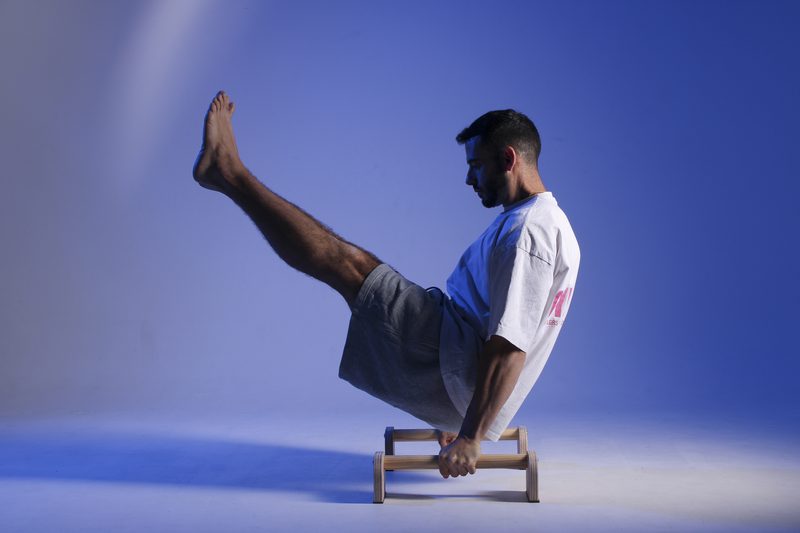 Iván en V-sit sobre las paralelas, con las piernas elevadas en uve
